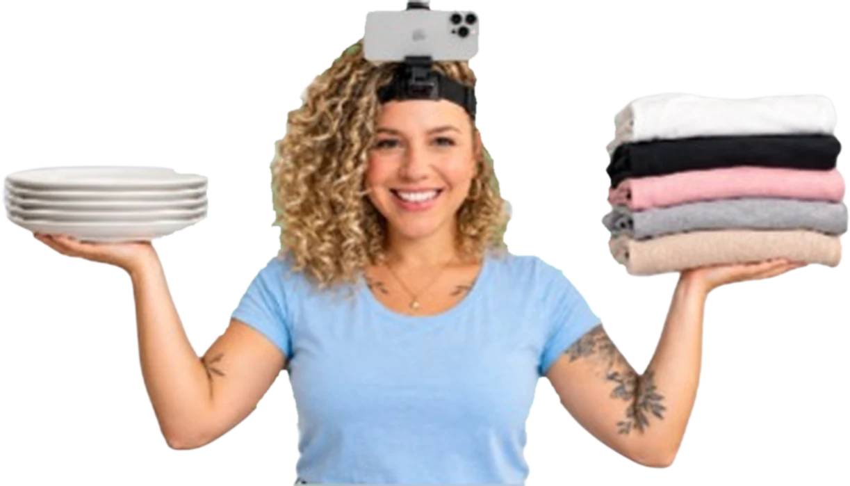 Camila Vieira com o celular preso na testa, segurando pratos e roupas dobradas